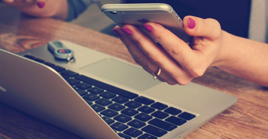A Girl Sitting on a Chair with a Laptop Open and Holding a Mobile
